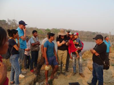 Community members gathered around field worker with digital camera